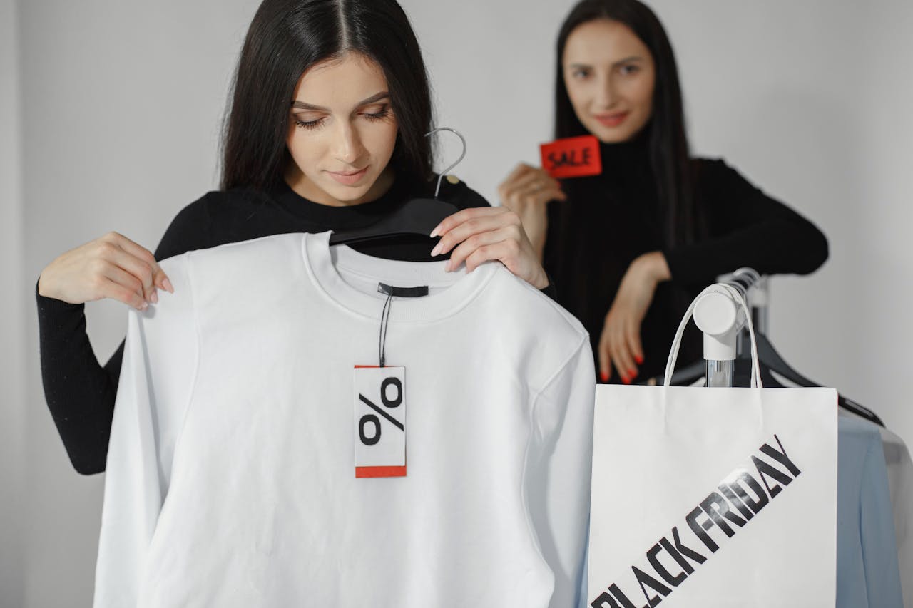 Two women enjoying Black Friday shopping with discounts and deals on clothes.