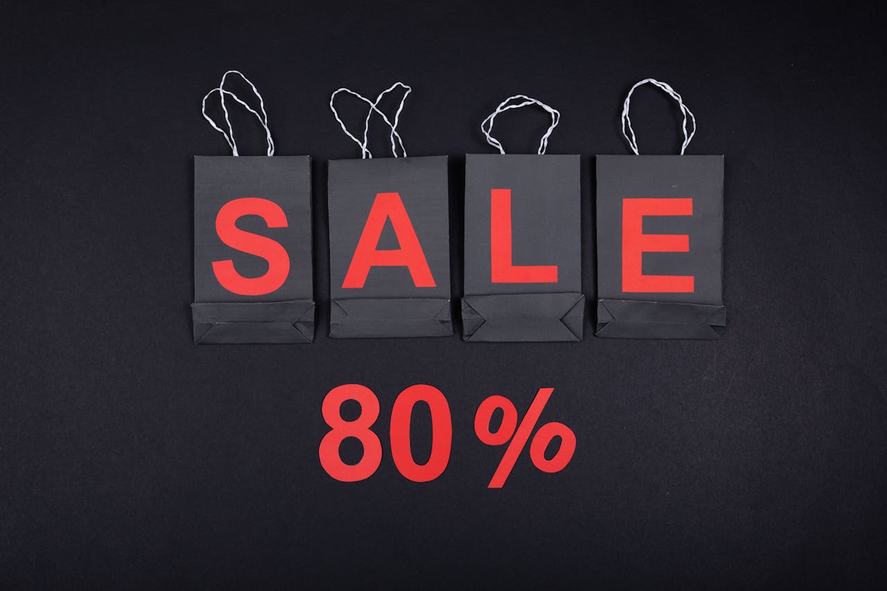 Highlighting a sale with 80% discount using black shopping bags and bold red text.